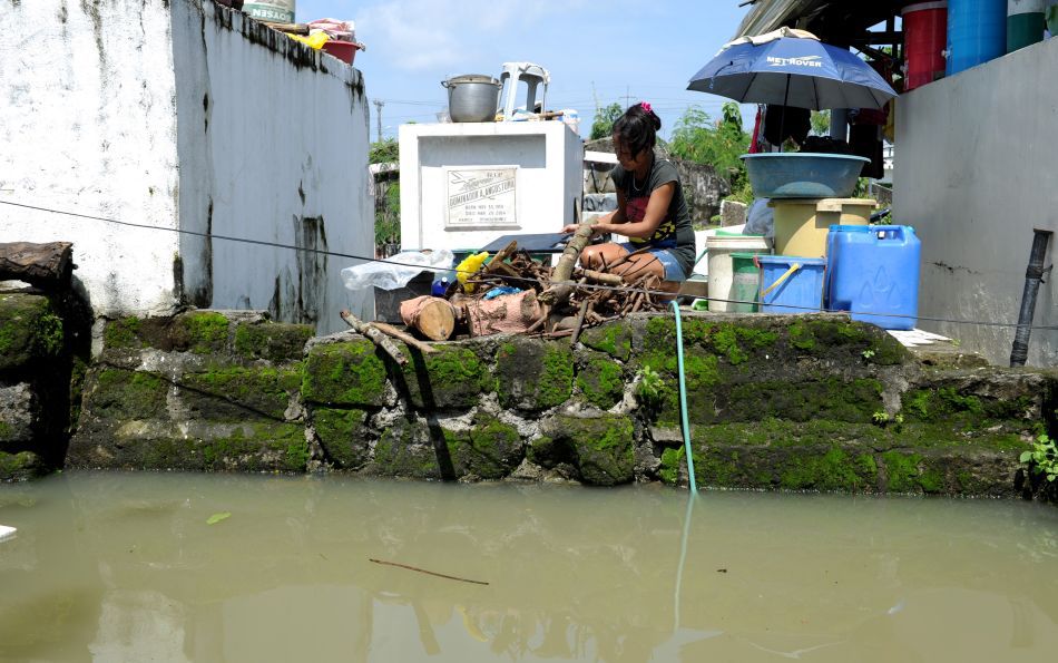 O femeie usucă lemne de foc lângă un mormânt ce a servit drept casă temporară a familiei sale în timpul inundaţiilor din oraşul Calumpit situat la nord de Manila (Filipine), 11 August 2012
