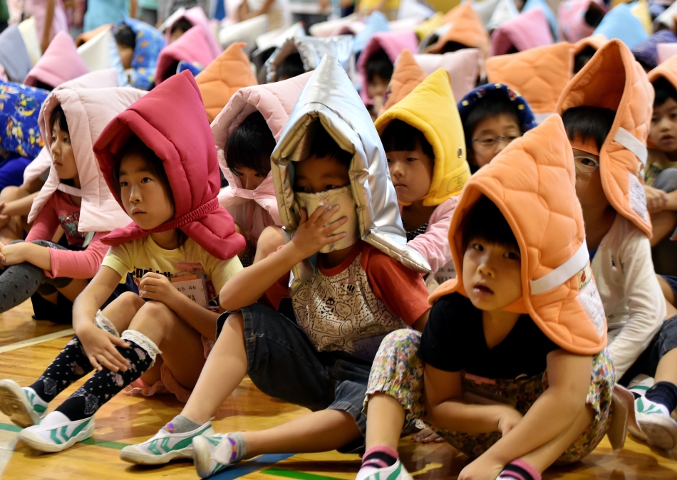 Copiii poartă glugi anti-incendiu în cadrul exerciţiilor